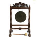 A Victorian oak and brass dinner gong, surmounted with pierced carved scrolls and a pair of mythical