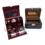 A burgundy leather travelling vanity case with fitted interior, holding brushes, looking glass
