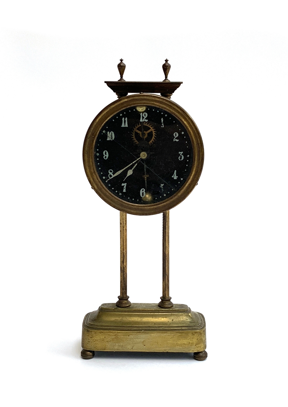 An early 20th century brass gravity clock, visible movement, the glass dial cracked, white painted