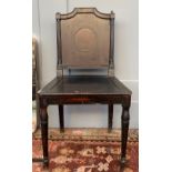 A 19th century ebonised hall chair, the back with circular brass motif