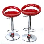 A pair of chrome adjustable barstools with shaped red seats, seat approx. 68cmH