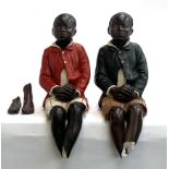 Two painted plaster figures of seated boys (af)