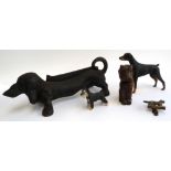 A cast iron boot scraper in the form of a dachshund, a brass English setter door knocker, a carved