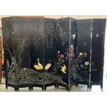 A 1920s eight fold Chinese lacquered screen, depicting songbirds, cranes and foliage carved in