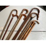 A collection of 11 various walking sticks, one with silver knop, another with silver collar