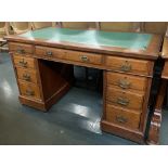 A 20th century oak pedestal desk, green tooled skiver, with the traditional arrangement of nine