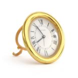 A Cartier desk clock, the oval gold plated desk clock with quartz movement, white dial with Roman