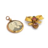 A Victorian yellow metal bow brooch, set with two stones, with suspended heart pendant enclosing