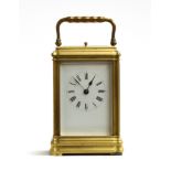 A brass carriage clock with bevelled glass and white enamel dial and Roman numerals, repeat