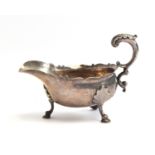 A late Victorian silver sauce boat, wavy edge, acanthus capped scroll handle, raised on leaf