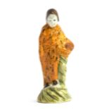 An 18th century Astbury-Whieldon figure of a woman with mustard glaze dress holding flower basket,