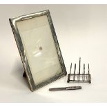 A small silver four division toast rack; a silver penknife/letter opener; and a white metal photo