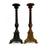 A pair of cast iron candlestick holders on tapering columns, the tripod base with mask decoration,