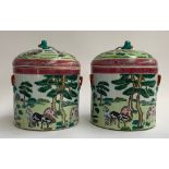 A pair of Chinese famille rose lidded pots depicting horses is a mountainous landscape, each with