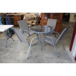 A metal and glass garden table with four chairs