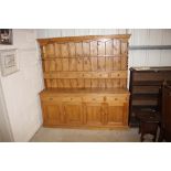A large stripped pine dresser raised on cupboard base