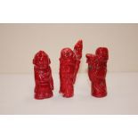 Three coral coloured carvings of figures