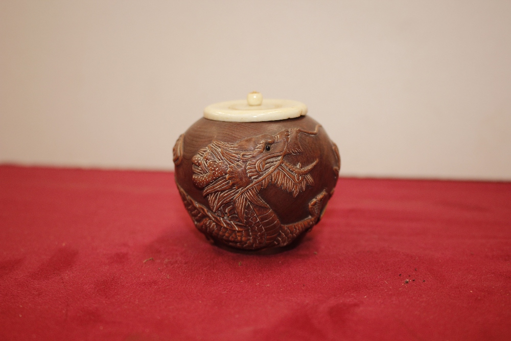 An oriental carved wooden jar with bone cover, of