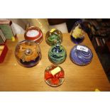 A collection of seven various coloured glass paperweight