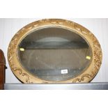 An oval gilt framed, floral decorated, bevel edged