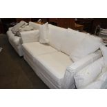 A cream two seater settee with lose covers and cus