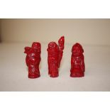 Three coral coloured carvings of figures