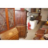 An antique oak floor standing corner cupboard