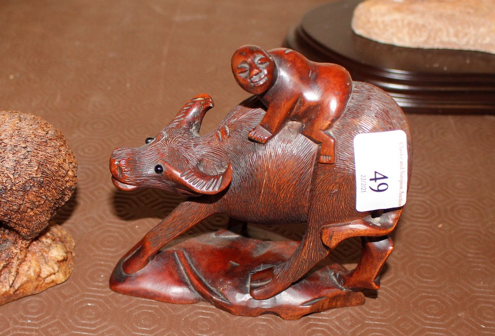 A carved hardwood figure of a boy riding a water b