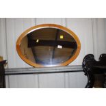 An oval teak framed wall mirror