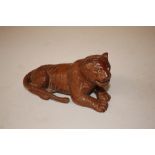 A carved wooden model of a recumbent tiger