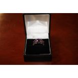 A white metal ring set three amethyst coloured sto