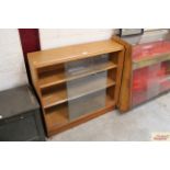 A mid-20th Century light oak bookcase enclosed by