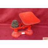 A set of red painted kitchen scales and weights