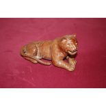 A carved wooden model of a recumbent tiger
