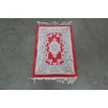 An approx. 3' x 2' red Chinese patterned wool rug