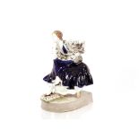 A Goldscheider pottery figure of a seated lady, in blue dress, her foot resting on a cushion on