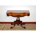 A Victorian walnut serpentine fronted card table, raised on a baluster column with carved