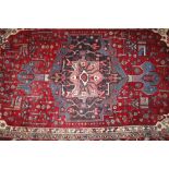 A Middle Eastern rug, having multi floral stylised decoration on a deep red and blue ground, 195cm x