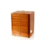 A contemporary light wood and brass mounted nine drawer trinket cabinet, with locking bar mechanism,