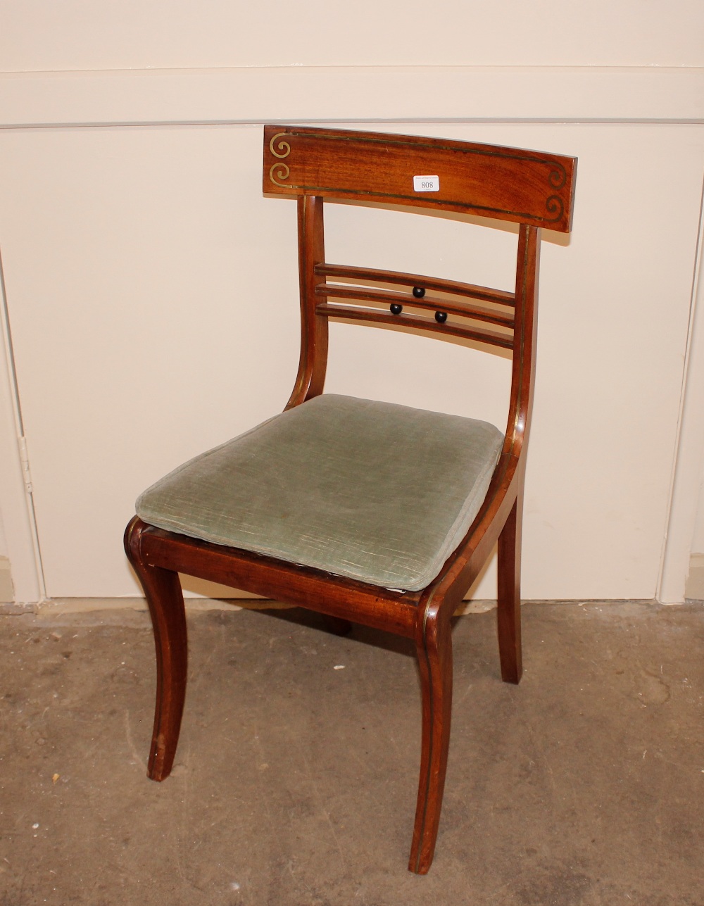 A set of six Regency mahogany brass inlaid dining chairs, having ball and rail backs, loose swab
