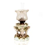 A 19th Century Dresden porcelain table oil lamp, the reservoir supported by four cherubs with