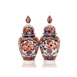 A pair of 19th Century Japanese Imari porcelain vases and covers, the ribbed bodies painted with