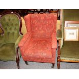 An Edwardian wing back armchair, raised on square tapering supports terminating in brass caps and