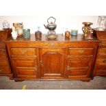 A 19th Century oak dresser base, fitted central cupboard enclosed by a fielded arched panelled door,