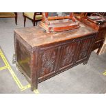 An antique oak coffer, having triple panelled carved front raised on square section supports,