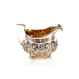 George III silver cream jug, having foliate embossed decoration, raised on ball feet having gilded