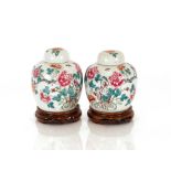 A pair of Chinese Famille Rose ginger jars, and covers raised on carved hardwood stands, 20cm high