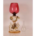 A Moore porcelain table oil lamp, profusely decorated with cherubs playing musical instruments and