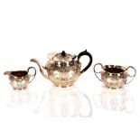 An Edwardian three piece silver tea set, with raised foliate garland and swag decoration, gilded