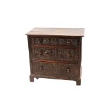 An antique carved oak chest fitted three long graduated drawers, 77cm wide